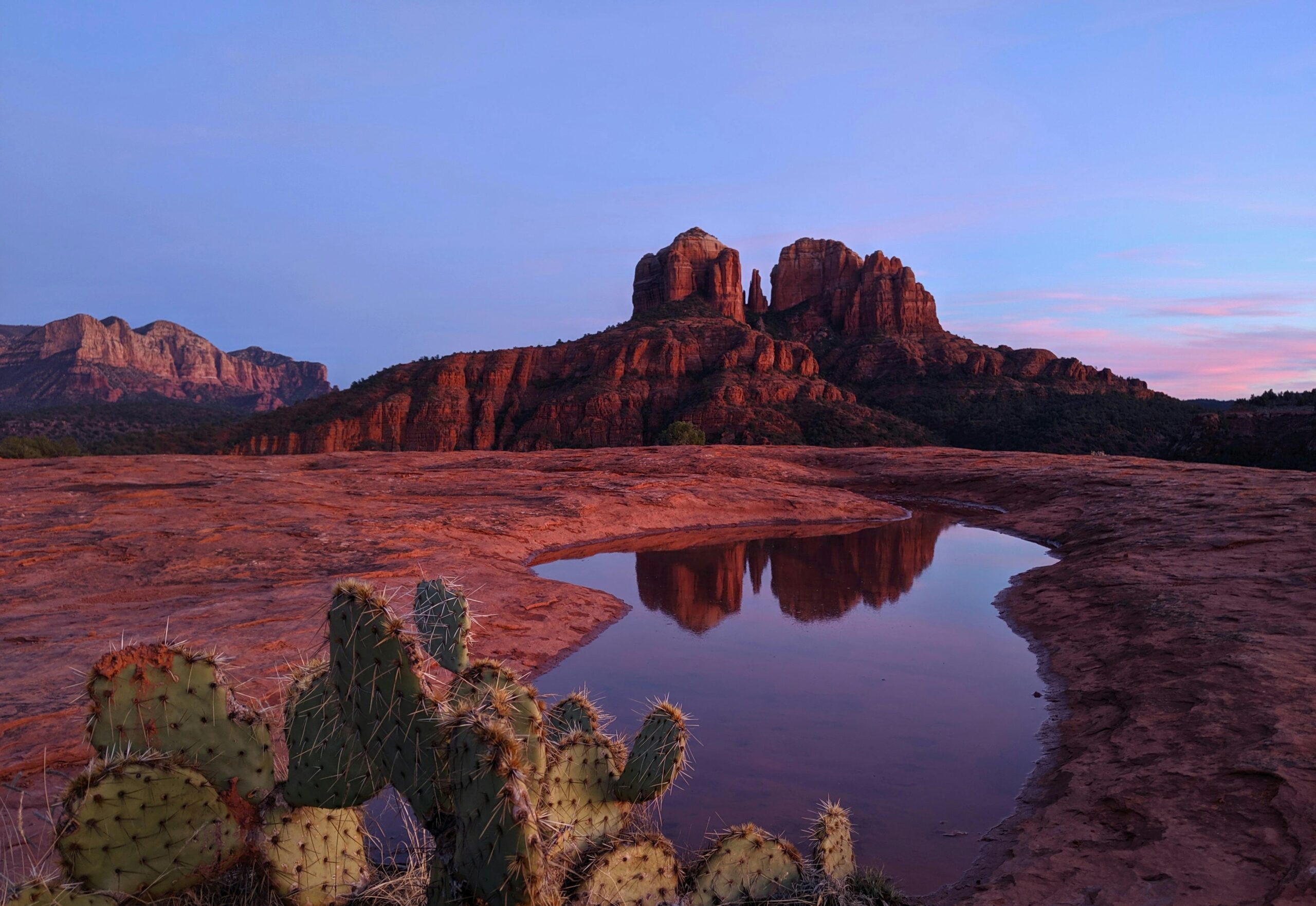 Stunning view of Cathedral Rock in Sedona, Arizona, reflecting in a puddle during sunset.